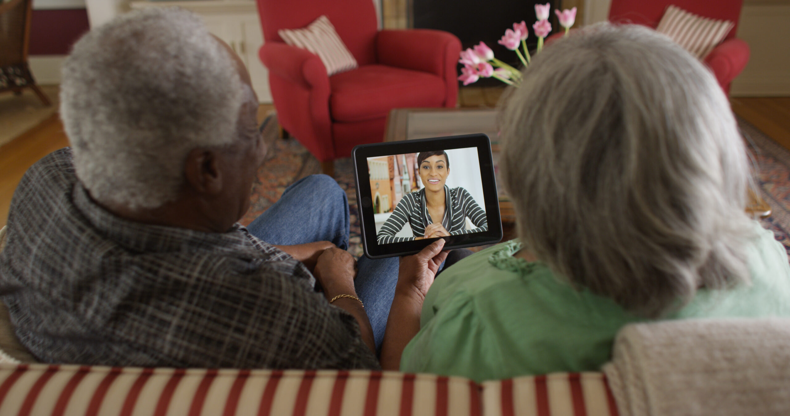 Happy senior black couple video chatting with granddaughter